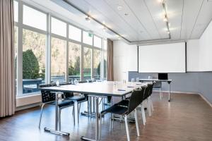 因特拉肯Hapimag Ferienwohnungen Interlaken的一间会议室,配有大桌子、椅子和白色屏幕