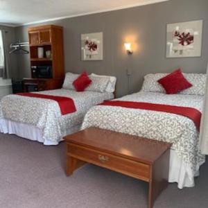 霍尔德内斯Yankee Trail Motel的一间卧室配有两张红色和白色床单