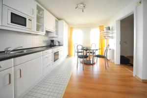威廉港Helgolandhaus的厨房配有白色橱柜和桌椅