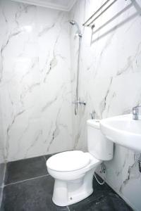 美娜多万鸦老梅尔斯宾馆的白色的浴室设有卫生间和水槽。
