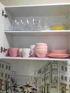 纳尔瓦约埃苏Karja 5 Apartment的架子上装有盘子和碗子及玻璃杯的架子