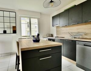 多维尔Appartement des Arts的厨房配有黑色橱柜和木制台面