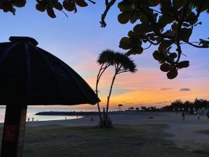 北谷町サンセットビーチホテル的棕榈树海滩上的日落