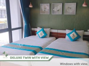 富国FLORA Hotel Phu Quoc的配有两张床铺的蓝色和白色枕头
