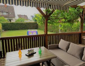 腓特烈港Familienfreundliches Ferienhaus AMARA mit Garten und Terrasse - Friedrichshafen am Bodensee的露台配有桌子和沙发,位于甲板上