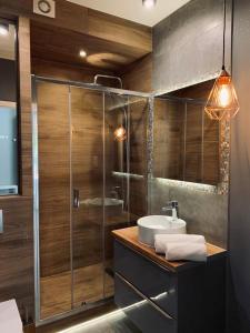 波别罗沃Apartamenty Silence Baltic Indygo的一间带玻璃淋浴和水槽的浴室