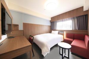 鹿儿岛鹿儿岛金生町里士满酒店的酒店客房,配有一张床和一张红色的沙发
