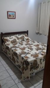 瓜拉派瑞Apto Aconchegante Enseada Azul com Wi-Fi的卧室内的一张床位,配有棕色和白色的毯子