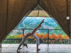 伦邦特日兹拉度假酒店 - 格拉姆营地的一位在窗前摆着瑜伽姿势的女人