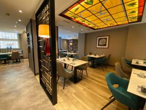 科隆莱斯基辰酒店的餐厅设有桌椅和彩色玻璃天花板