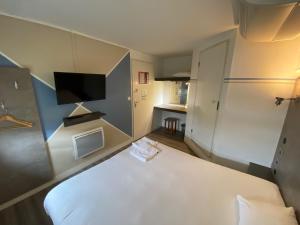 圣萨蒂南勒芒法斯特酒店的小房间设有白色的床和电视