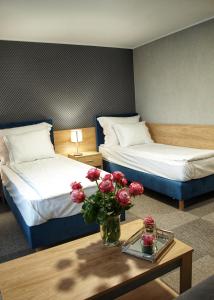 格鲁德柴兹Hotel Rudnik的酒店客房,设有两张床和一张鲜花桌。