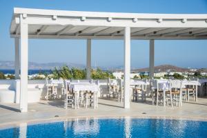 圣安娜纳克索斯Cycladic Islands Hotel & Spa的一个带白色椅子的庭院和一个游泳池