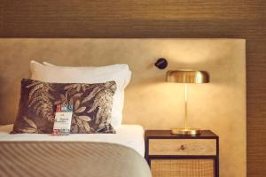 阿纳姆阿纳姆凡德瓦克酒店的床上配有枕头,床头柜上配有灯