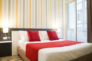 那不勒斯奇玛罗莎酒店的一间卧室配有红色和白色枕头的床