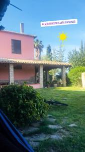 DolianovaAgriturismo Santu Marcialis的天空中阳光下的粉红色房子