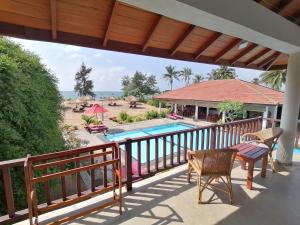AmbalantotaLadja Beach Resort的一个带桌椅的阳台和一个游泳池