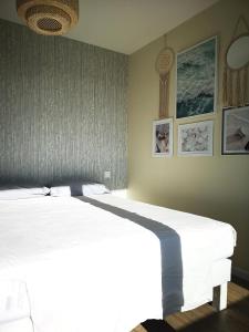 米米藏Les Terrasses de l'Océan的卧室配有一张白色大床和墙上的时钟