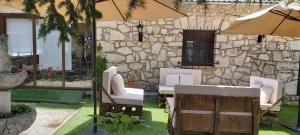佩德拉萨Casa Rural Pedraza的石头建筑前的庭院配有椅子和遮阳伞