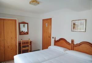 别尔萨皮里内奥斯梅里兹旅舍的一间卧室配有两张白色的床和木制床头板