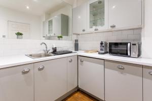 泰恩河畔纽卡斯尔Stylish Apartment in the heart of Newcastle centre的白色的厨房配有微波炉和水槽