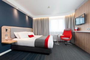 伦敦伦敦汉墨史密斯智选假日酒店的酒店客房,配有一张床和一张红色椅子