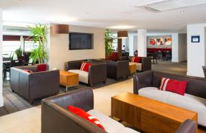 米尔顿凯恩斯快捷假日米尔顿凯恩斯酒店的酒店大堂设有沙发、椅子和电视。