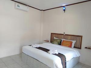 龙目岛库塔Jeri Home Stay的一间卧室配有一张带白色床单和弓的床铺