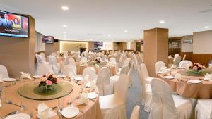 关丹E-RED HOTEL KUANTAN的宴会厅配有白色的桌子和白色的椅子