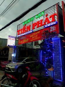 金瓯KHÁCH SẠN TIẾN PHÁT的停在餐厅前面的汽车,餐厅有 ⁇ 虹灯标志