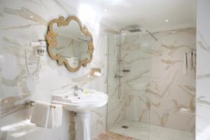 卡尔维木兰花酒店的浴室配有盥洗盆和带镜子的淋浴