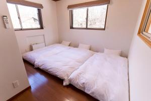 SaikuboGuest house Japan Kita-Karuizawa的带2扇窗户的客房内的2张床