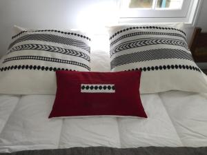 阿尔宗La petite Escarpolette的一张带黑白枕头和红色枕头的床