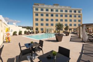 埃斯托利尔Vila Gale Estoril - Adults Friendly的一座带游泳池和椅子的酒店和一座建筑