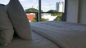 亚松森START Villa Morra Rent Apartments的一张带白色床单和枕头的床,位于窗户前