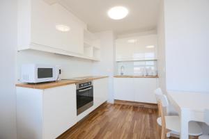 派尔努Lys Apartments City Center的厨房配有白色橱柜、桌子和微波炉