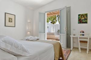 奥里亚Palombara Masseria & SPA - Adults Only的白色的卧室设有床、桌子和窗户