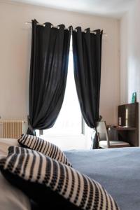 拉兰Hôtel d'Ossau的一间卧室配有黑色窗帘和一张带两个枕头的床