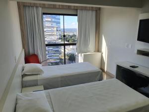 巴西利亚巴西利亚阿帕特酒店的酒店客房设有两张床和大窗户。