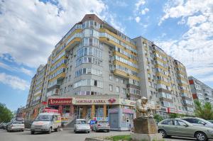 鄂木斯克Omsk Sutki Apartment on 70 let octyabrya 10/3的一座大型建筑,前面有汽车停放