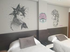 维多利亚-加斯特伊兹Hotel Arts - Gasteiz Centro的墙上贴有海报的房间里设有两张床