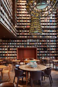 苏黎世B2 Hotel Zürich的图书馆配有桌椅和一堵大墙的书籍