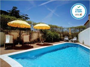 帕尔梅拉Casa de Atalaia的一个带两把遮阳伞和两把椅子的游泳池