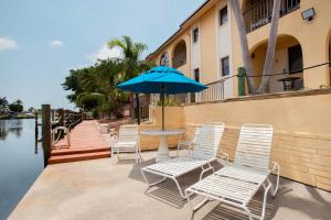 珊瑚角OYO Waterfront Hotel- Cape Coral Fort Myers, FL的桌子、椅子和水边的雨伞