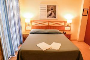 阿祖罗港朱利亚别墅酒店的一间卧室,配有一张床铺和两张纸