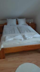 下厄尔什Rege apartman的一张带白色床单和枕头的大型木制床