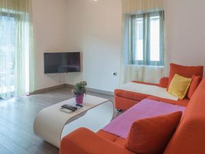 科托尔温德罗斯公寓的客厅配有橙色和白色家具以及平面电视。
