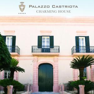 阿莱齐奥Palazzo Castriota的粉红色的建筑,设有绿门和阳台