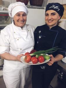沃罗赫塔Oksamit Resort的两个女人在一间厨房里,拿着一盘蔬菜