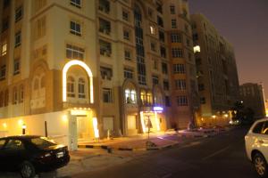 多哈White Moon Al Sadd的一座大型建筑,前面有汽车停放